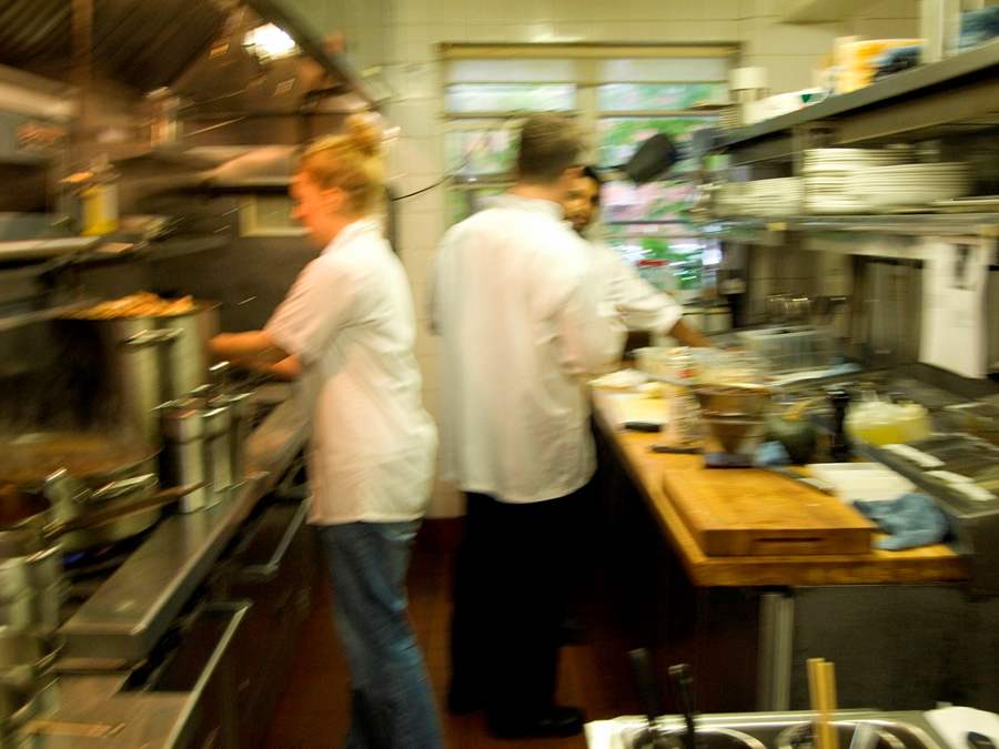 cooks working in a busy and narrow kitchen