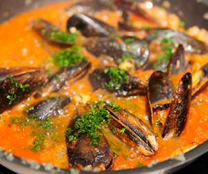 clams stewing in a red on the stove